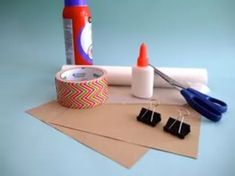 craft supplies including scissors, tape and glue on top of brown paper with blue background