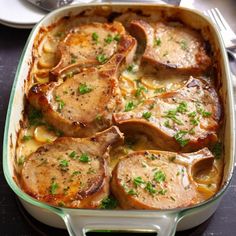 a casserole dish with pork chops and cheese in it on a table