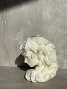 a white sculpture sitting on top of a table next to a gray wall and floor