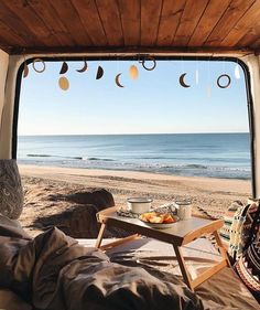 a table with food on it sitting in front of an open window overlooking the beach