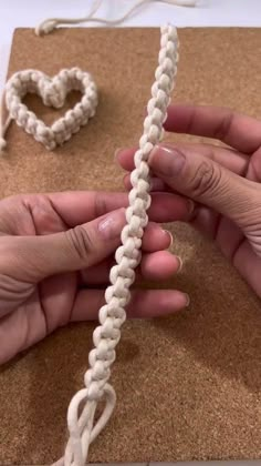 two hands are working on a piece of white yarn that has been braided together