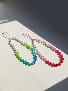 two colorful bracelets sitting on top of a white table next to a bottle of water