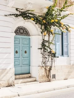 a blue door with yellow flowers in front of it on the side of a building