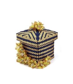 a blue and gold beaded box sitting on top of a white surface