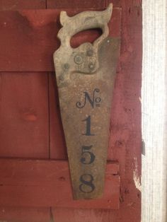 an old fashioned door handle with the number one on it's side, hanging from a red wooden wall