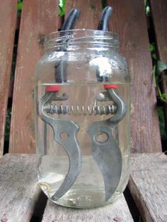 a mason jar with scissors in it sitting on a wooden bench outside, ready to be used as a gadget