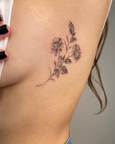 a woman's stomach with flowers and leaves tattooed on her side, in black ink