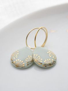 two gold hoop earrings sitting on top of a white plate