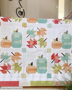 a quilted table runner with pumpkins and leaves on the front, along with a potted plant