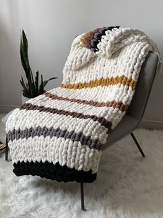 a crocheted blanket sitting on top of a chair next to a potted plant