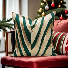 a red chair with two pillows on it and a christmas tree in the background