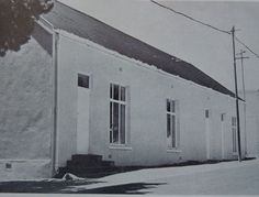 an old black and white photo of a small building with two windows on the side