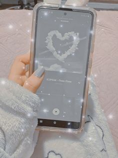 a person holding an electronic device in their hand with some lights on the screen and she is wearing a white sweater