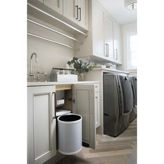 a kitchen with white cabinets and stainless steel appliances, including a trash can in the middle