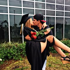 a man and woman are kissing in front of a building with flowers on it's lap