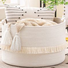 a large white basket with tassels on top