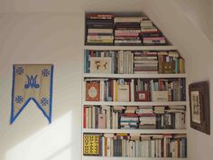 a bookshelf filled with lots of books next to a painting on the wall