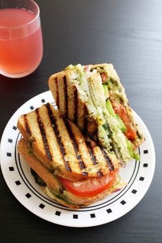 a grilled sandwich on a plate next to a glass of juice