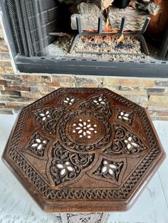 an ornate wooden table sitting in front of a fire place