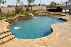 an outdoor swimming pool with steps leading up to it and a waterfall in the middle