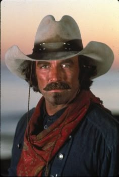 a man in a cowboy hat and scarf with a moustache on his face