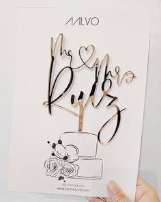 a hand holding up a cake topper with the words mr and mrs on it