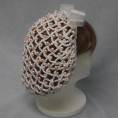 a woman's head wearing a white knitted hat with pink pearls on it