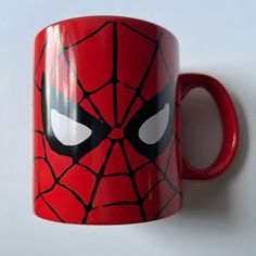 a red mug with a spiderman face painted on it