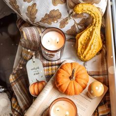 two candles and some pumpkins on a blanket