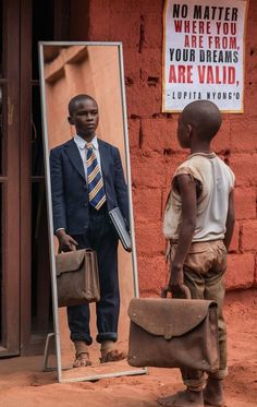 a man standing in front of a mirror next to a little boy holding a briefcase