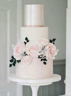 a three tiered white cake with pink flowers on top