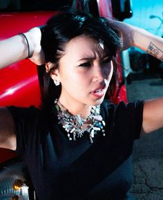 a woman sitting on the ground with her hands behind her head and wearing a black shirt