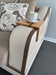 a couch with a cup and saucer on top of it next to a pillow