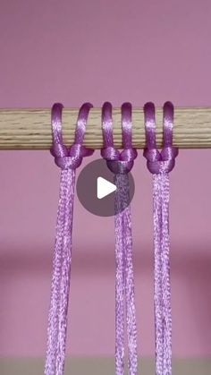 the video is showing how to tie an object with purple thread and wooden dows