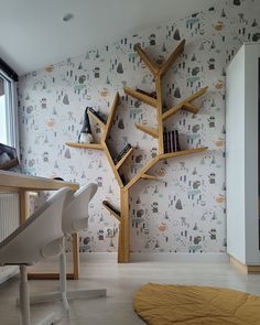 a room with bookshelves, desk and chair next to a wallpapered tree