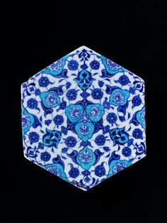 a blue and white hexagonal object with flowers on it's sides, against a black background