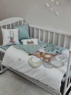 a white crib with blue sheets and pillows on it