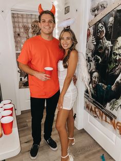 a man and woman standing next to each other in front of a wall with pictures on it