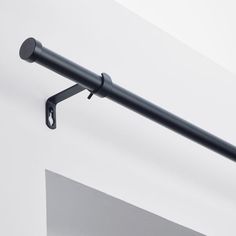 a metal pole with a black handle hanging from it's side next to a white wall