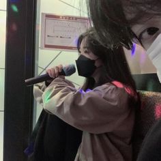 a woman holding a microphone in front of a man wearing a face mask and covering his mouth