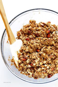 a glass bowl filled with granola and yogurt next to a wooden spoon