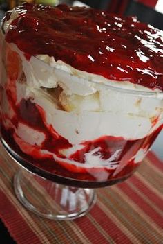 a layered cake with white and red icing on a glass stand, ready to be eaten