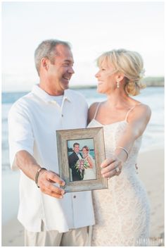 a man and woman standing on top of a beach holding an old photo in front of them