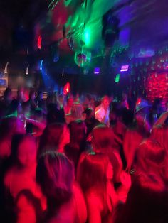 a group of people dancing in a club with neon lights on the walls and floor