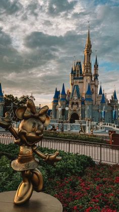 there is a statue of mickey mouse in front of the castle