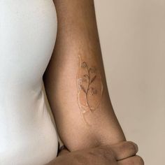 a woman's arm with a tattoo on it, showing the outline of a flower