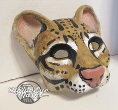 a close up of a cat mask on a white surface with a black and brown stripe