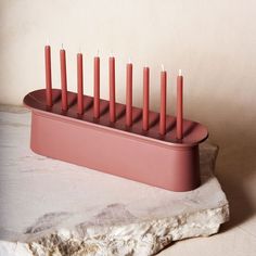 a pink candle holder sitting on top of a rock