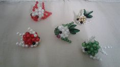 four different types of beaded flowers on a white cloth with beads attached to them