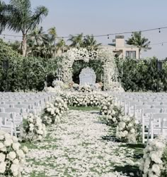 an outdoor wedding setup with white flowers and greenery on the lawn, surrounded by palm trees